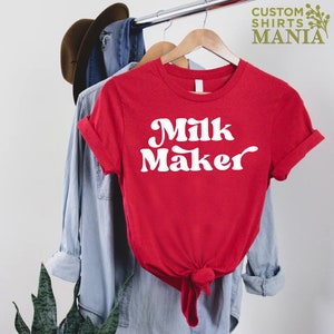 May include: Red t-shirt with white text that says "Milk Maker" in a retro font.