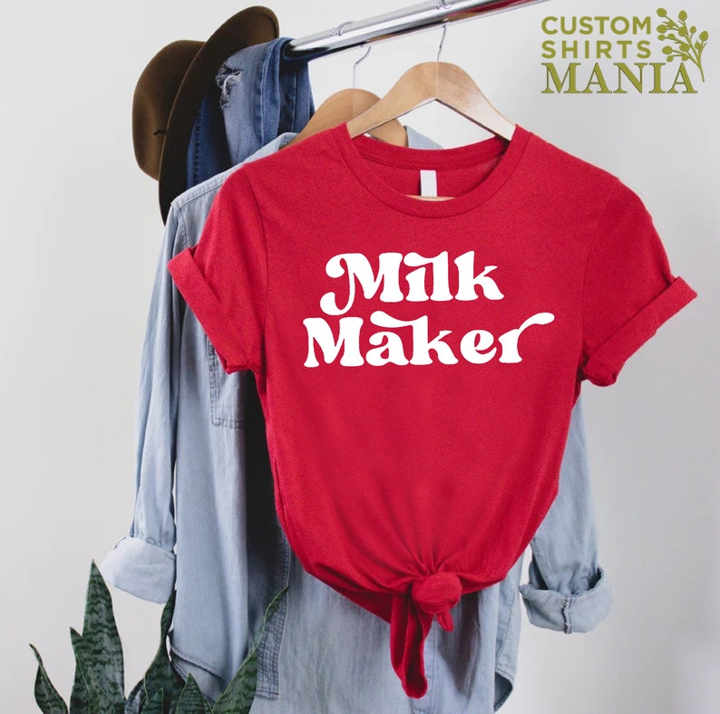 May include: Red t-shirt with white text that says "Milk Maker" in a retro font.