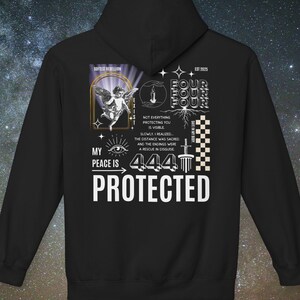 May include: Black hoodie with white graphic text and illustrations. The design includes an angel, eye, and the words "MY PEACE IS 444 PROTECTED". Additional text includes "NOT EVERYTHING PROTECTING YOU IS VISIBLE".