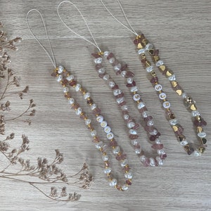 May include: Four phone charms with pink and white beads and gold accents. The charms spell out "LOVE", "SUGAR", and two charms spell out "S" and "R".