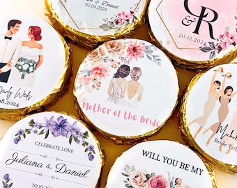 May include: Assortment of round chocolate favors with personalized labels featuring floral designs, wedding-related text, and illustrations of couples. The labels include text such as "Newly Weds", "Mother of the Bride", "Will You Be My", and "Celebrate Love".