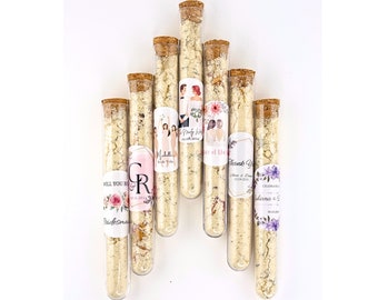 May include: Set of eight clear glass test tubes with cork tops filled with a white powder. Each tube has a personalized label with floral designs and text, such as "Will You Be My Bridesmaid?" and "Thank You for Celebrating with Us".