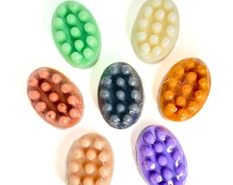 May include: Seven oval-shaped bath soap bars with textured bumps. The soaps are in various colors: green, white, orange, gray, peach, and purple.