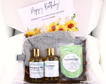 May include: A gift box filled with a gray fuzzy eye mask, two bottles of eucalyptus and mint massage and body oil, and a bag of eucalyptus and mint bath salts. The box also includes a card that says "Happy Birthday!" and "Sending you warm wishes on your special day! With love, [NAME]"