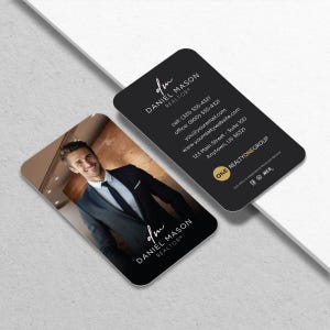 May include: Two black business cards with rounded corners. One card features a photo of a smiling man in a suit, with the text "DANIEL MASON REALTOR" in white. The other card has contact information in white text.