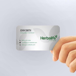 a hand holding a business card that says herblife