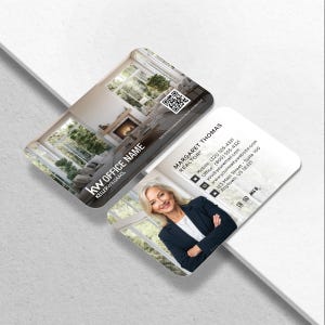 May include: Two business cards with rounded corners. One card features a living room scene with a fireplace. The other card displays a woman in a blazer with contact information, including the name "Margaret Thomas, Realtor". The Keller Williams logo is visible.
