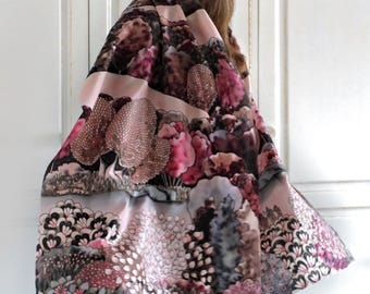 May include: A hand-painted silk scarf with a botanical design in shades of pink, purple, and gray. The scarf features a detailed pattern of flowers and foliage, with the text "Hand painted silk scarf".