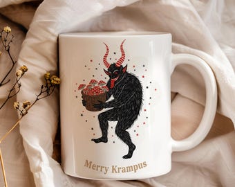 Puede incluir: Taza de cerámica blanca con una ilustración de Krampus. El diseño presenta un Krampus negro y peludo con cuernos rojos y lengua roja, sosteniendo una cesta de setas. El texto "Merry Krampus" está impreso debajo.