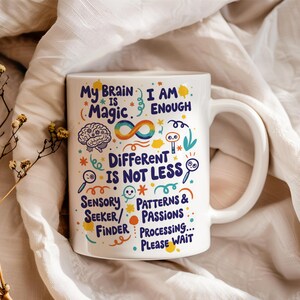 Pode incluir: Caneca de cerâmica branca com uma alça grande, com texto e ilustrações coloridas. O texto inclui frases como "My Brain is Magic" e "Different is Not Less". A caneca tem gráficos de cérebro, símbolo de infinito e lupa.