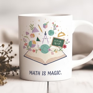Peut inclure: Mug en céramique blanche avec une anse, portant l'inscription "MATH IS MAGIC." La tasse est ornée d'illustrations colorées de symboles mathématiques, de formes géométriques, de fleurs et d'un livre ouvert. Le design comprend un petit tableau noir avec des équations.