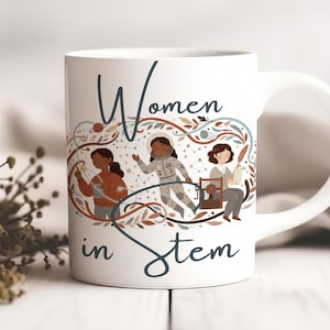 Peut inclure: Mug en céramique blanche avec l'inscription "Women in Stem". Le mug présente des illustrations de trois femmes dans les domaines STEM, entourées d'un motif floral et céleste décoratif. La tasse a une anse blanche.
