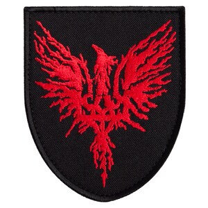 May include: Black embroidered patch featuring a red phoenix design. The phoenix is depicted with outstretched wings and intricate detailing. The patch has a black border and a shield shape.