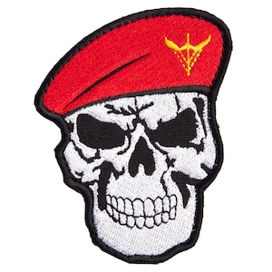 May include: Embroidered patch featuring a white skull wearing a red beret. The beret has a gold emblem. The skull has black eye sockets and a detailed jawline. The patch has a black border.