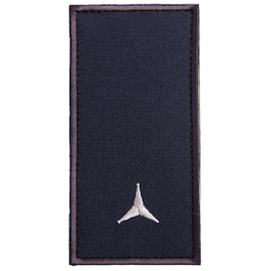 Pode incluir: Um patch retangular azul marinho com uma borda cinza. Um símbolo bordado branco está centrado na parte inferior. O patch tem uma aparência texturizada.