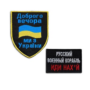 May include: Two black embroidered patches. One is shield-shaped with the Ukrainian flag and the text "Доброго вечора, ми з України" in blue and yellow. The other is rectangular with the text "Русский военный корабль иди нах*й" in white and red.