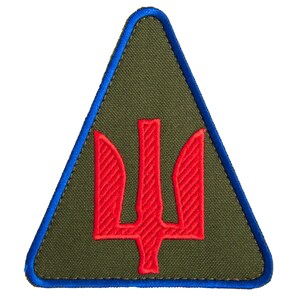 Może przedstawiać: Trójkątna naszywka z niebieską obwódką i zielonym tłem. Czerwony emblemat trójzębu jest wyśrodkowany na naszywce. Naszywka jest prawdopodobnie emblematem lub odznaką.