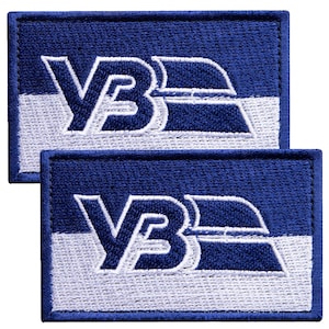 May include: Two embroidered patches with a rectangular shape. The patches feature a blue background with white horizontal stripes and the letters "VB" in white. The patches are bordered with blue stitching.