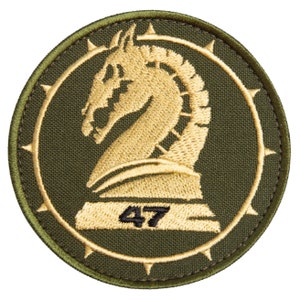 May include: A circular patch with a gold horse chess piece design inside a gold ring with spikes. The patch has a green background and a green border. The number "47" is printed in black at the bottom of the design.