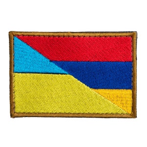 May include: Embroidered patch featuring a flag design with horizontal red and blue stripes, a blue triangle, and a yellow and blue lower section. The patch has a brown border.
