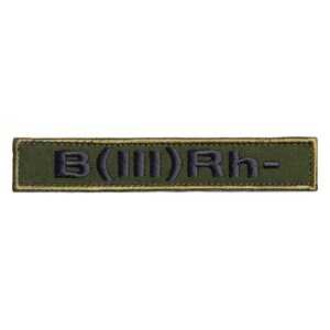 May include: Olive green rectangular patch with the embroidered text "B(III)Rh-" in black. The patch has a thin, tan border. The text is centered on the patch.