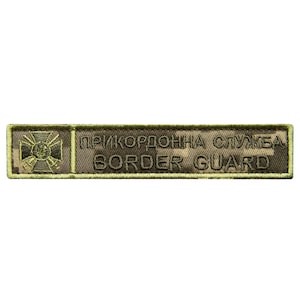 May include: A rectangular patch with a camouflage pattern and embroidered text. The patch features the words "BORDER GUARD" in English and Cyrillic text. A cross emblem is on the left side of the patch.