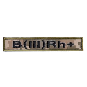 May include: A rectangular patch with the text "B(III)Rh+" embroidered in black on a camouflage background. The patch has a tan and green digital camouflage pattern and a dark green border.