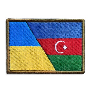 May include: Embroidered patch featuring the flags of Ukraine and Azerbaijan. The patch has a rectangular shape with a brown border. The Ukrainian flag is yellow and blue, while the Azerbaijani flag is red, green, and blue with a crescent moon and star.