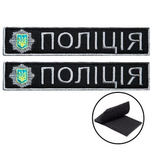 Pode incluir: Dois patches bordados pretos com a palavra "ПОЛІЦІЯ" em branco e um brasão ucraniano. Uma pequena inserção circular mostra um pedaço de velcro preto.