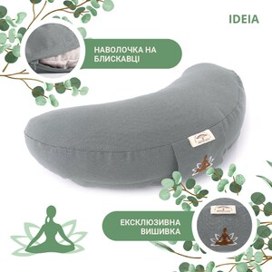 May include: A gray crescent-shaped yoga bolster with a zipper and embroidered logo. The bolster has a light gray fabric cover and is designed for meditation and yoga practices. The text "IDEIA" is visible in the upper right corner.