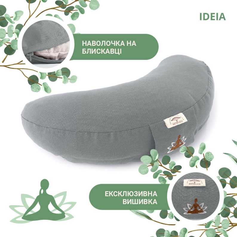 May include: A gray crescent-shaped yoga bolster with a zipper and embroidered logo. The bolster has a light gray fabric cover and is designed for meditation and yoga practices. The text "IDEIA" is visible in the upper right corner.