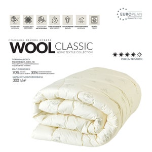 Puede incluir: Un edred&oacute;n de invierno cl&aacute;sico de lana plegado, de color crema, con un estampado de ovejas. El edred&oacute;n presenta el texto "WOOL CLASSIC HOME TEXTILE COLLECTION". El edred&oacute;n est&aacute; hecho de microfibra y tiene una densidad de 300 g/m2.