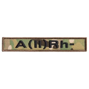 May include: A rectangular patch with a camouflage pattern background and black embroidered text. The text reads "A(II)Rh-". The patch has a brown border.