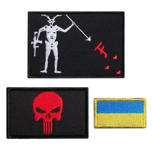 May include: Three embroidered patches: a black patch with a white skeleton figure holding a rifle and spear, a red skull on a black patch, and a Ukrainian flag patch with blue and yellow stripes.