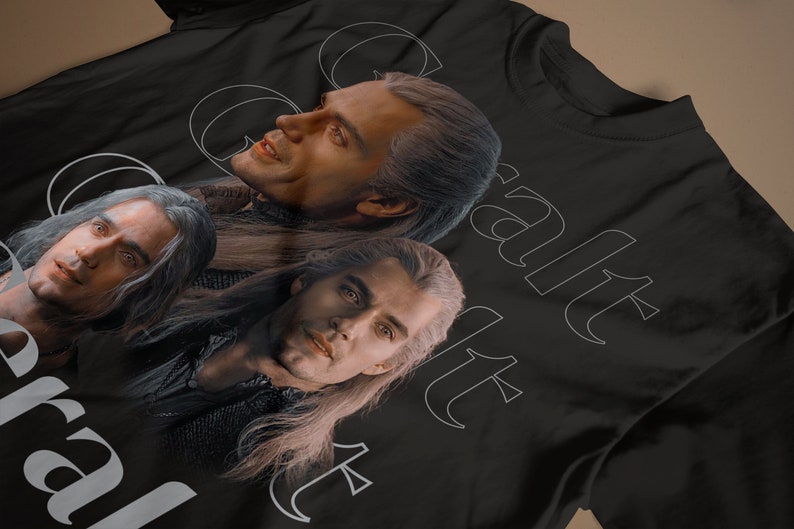 May include: Black t-shirt with a white graphic of three men with long hair. The text "Geralt" and "Yennefer" are printed on the shirt.
