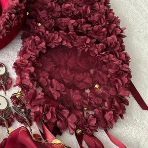 May include: A burgundy floral fabric with a sheer overlay and gold accents. The fabric is arranged in a circular shape and has a delicate, feminine feel.