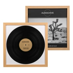 May include: Two framed prints. One features a black vinyl record with a gold label, the other a black and white desert landscape. Both are in light wood frames. The record label reads "AUDIOCHIVE" and "keep your music safe and sound."