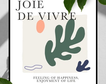 May include: A black and white framed print with the text "JOIE DE VIVRE" in black. The print features a green leaf, a pink circle, and a purple squiggle on a beige background. The text "FEELING OF HAPPINESS, ENJOYMENT OF LIFE" is below the image.