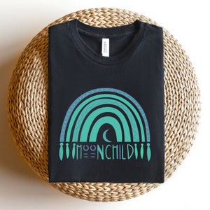 May include: Black t-shirt with a teal and purple rainbow design and the text "MOONCHILD" in a stylized font.