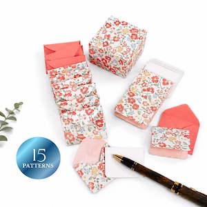 May include: A collection of stationery items, including small floral-patterned notebooks, matching envelopes, and a box. The notebooks and box feature a white background with red, yellow, and blue floral designs. The set includes a pen and a card. The image also shows a blue circle with the text "15 PATTERNS".