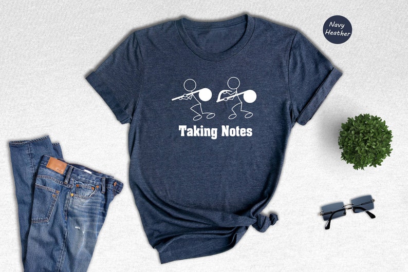 May include: A navy heather t-shirt with a white graphic of two stick figures holding musical notes. The text "Taking Notes" is printed below the graphic.