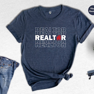 May include: Navy heather t-shirt with the word "REALTOR" repeated in white text with a red house icon in the centre of the word.