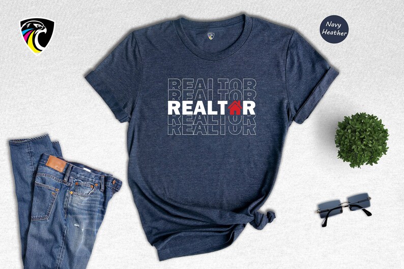 May include: Navy heather t-shirt with the word "REALTOR" repeated in white text with a red house icon in the centre of the word.