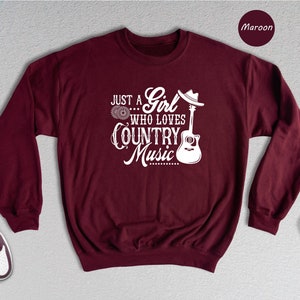 May include: Maroon sweatshirt with a white graphic that says "Just a Girl who loves Country Music" with a guitar and cowboy hat.