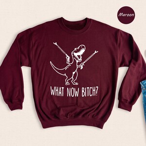 a sweater that says what now bitch? next to a pair of jeans and a