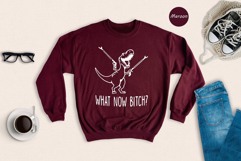 a sweater that says what now bitch? next to a pair of jeans and a