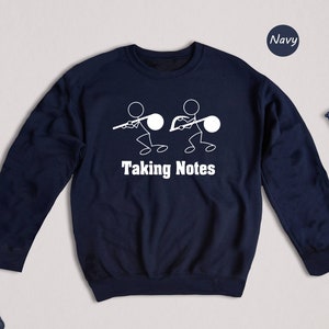 May include: Navy blue sweatshirt with a white stick figure design of two people taking notes. The text "Taking Notes" is printed below the figures.