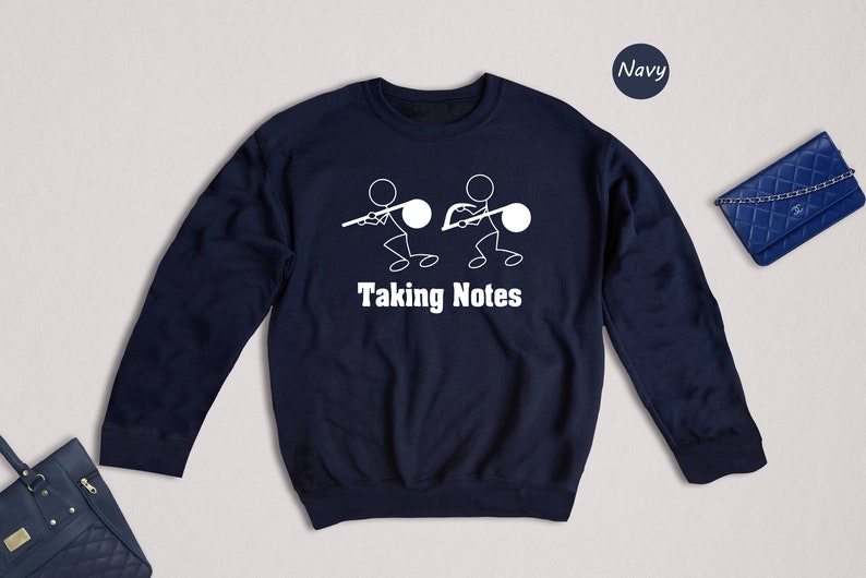 May include: Navy blue sweatshirt with a white stick figure design of two people taking notes. The text "Taking Notes" is printed below the figures.