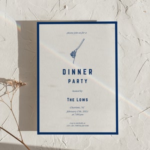 Op de afbeelding: Een witte uitnodigingskaart met een blauwe rand. De kaart heeft een eenvoudige illustratie van een bezem en de tekst "U bent van harte welkom voor een diner georganiseerd door The Lows Charlotte, NC op 17 februari 2023 om 19:00 uur"