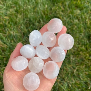 May include: A collection of ten white selenite tumbled stones. The stones are smooth and polished, with a slightly translucent appearance.